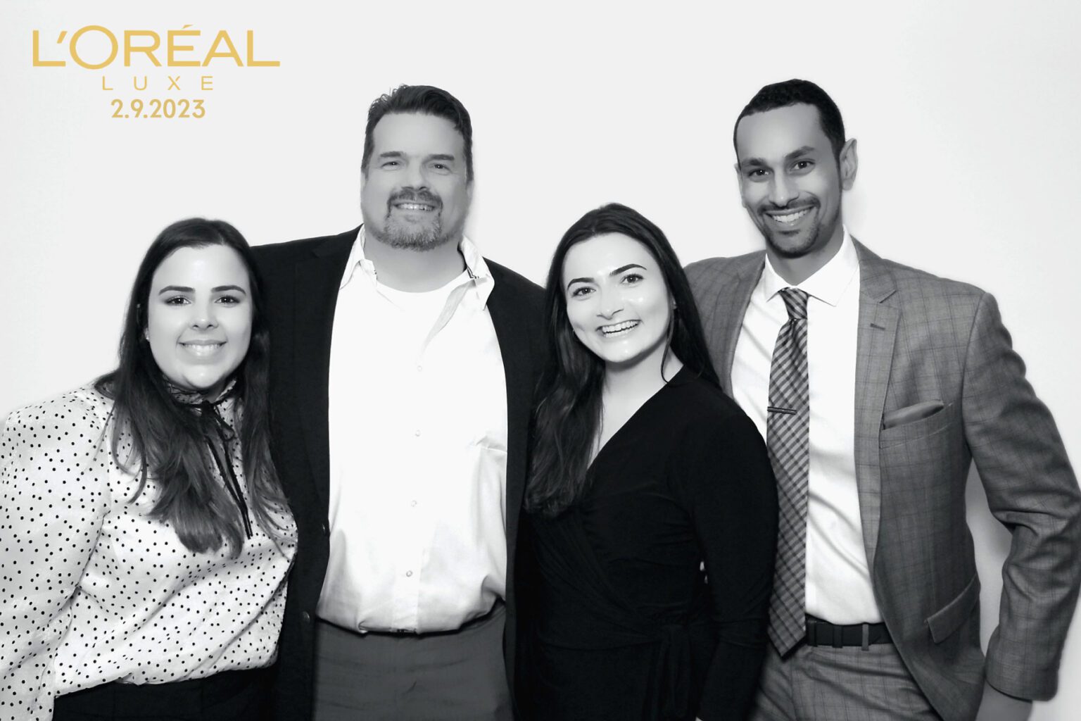 A group of professionals, dressed in formal black-and-white attire, pose for a classic, monochrome corporate portrait. - Milestone Photo Booths.