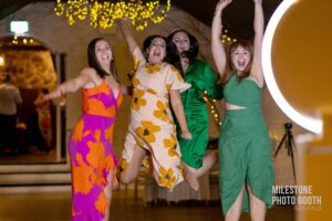 A group of women in vibrant floral dresses, celebrating with joyful energy at an elegant corporate gala at Milestone NJ.