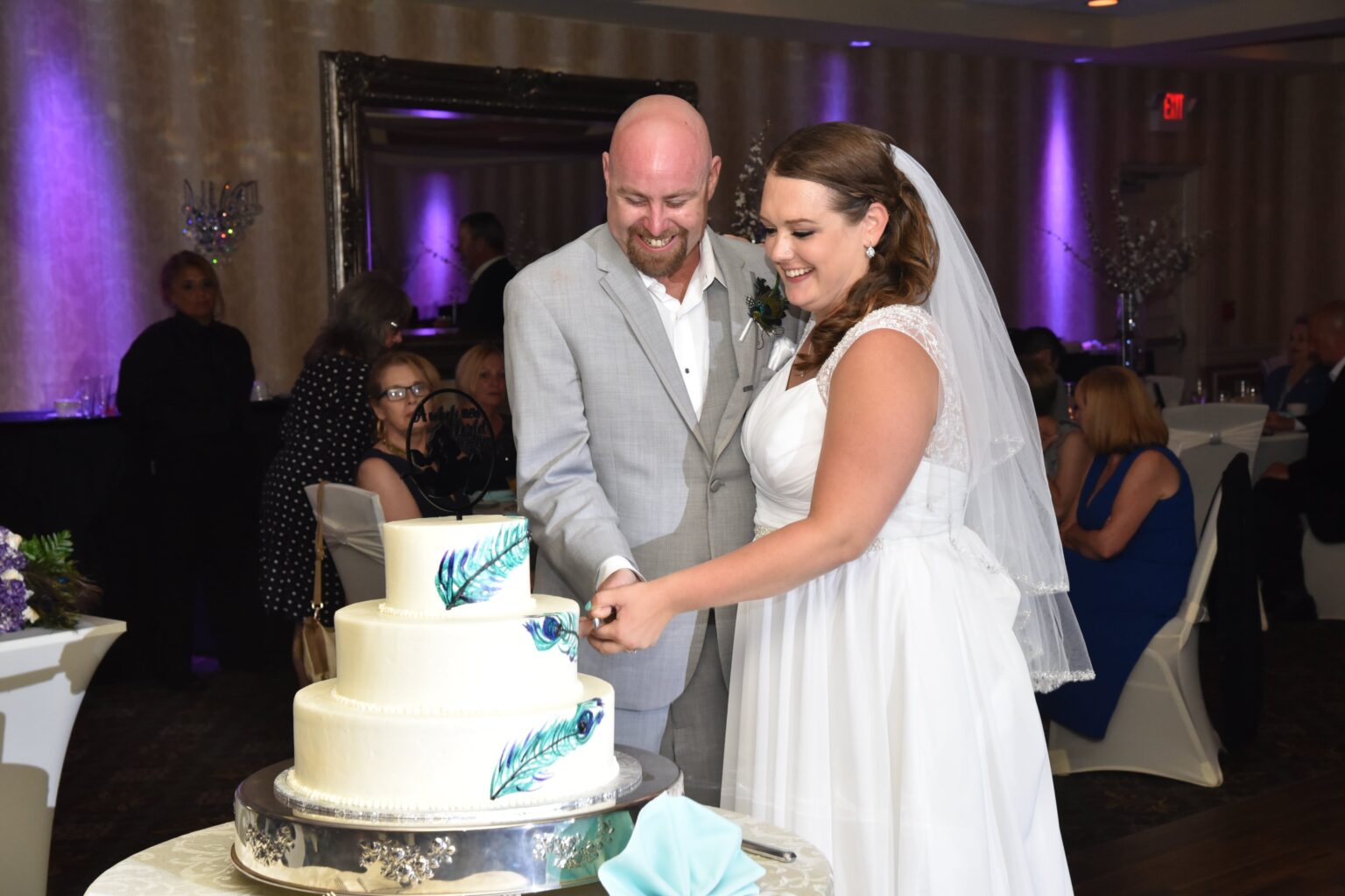 A wedding couple cutting their wedding cake in a grand ballroom - Milestone Photo Booths.