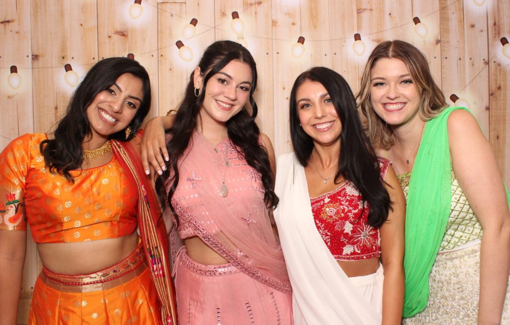 Guests dressed in colorful outfits posing - Milestone Photo Booths.