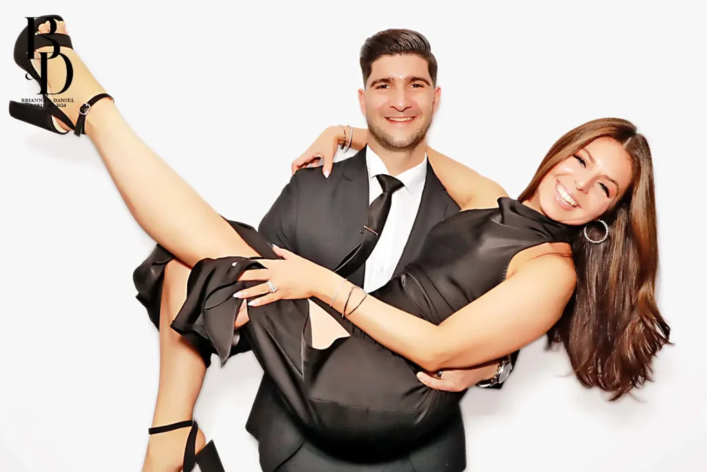 A couple having fun in the photo booth with the man lifting up his partner.