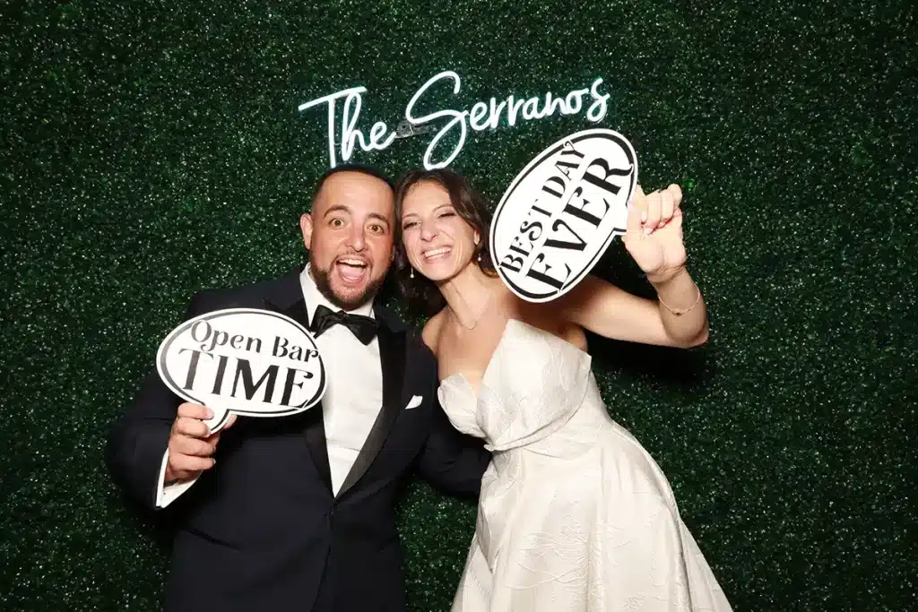 Bride and groom posing in a wedding photo booth with fun props