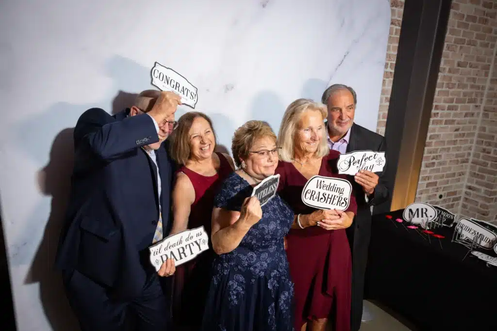 Guests posing with props in a wedding photo booth creating fun candid memories