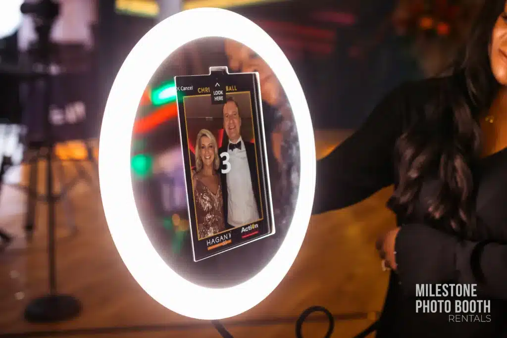 Milestone's Rainbow Ring Roaming Photo Booth ring light in action at a corporate event, displaying a live preview of guests on the screen during a photo session