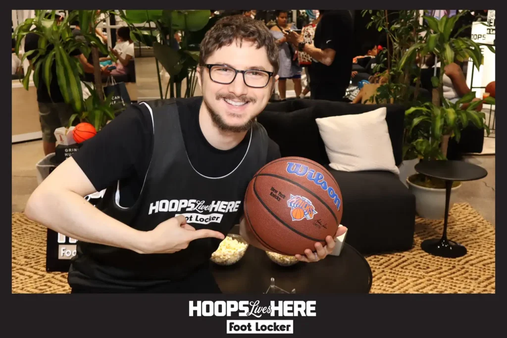 Guest holding a signed New York Knicks basketball at the Foot Locker Herald Square activation with the Hoops Lives Here photo overlay