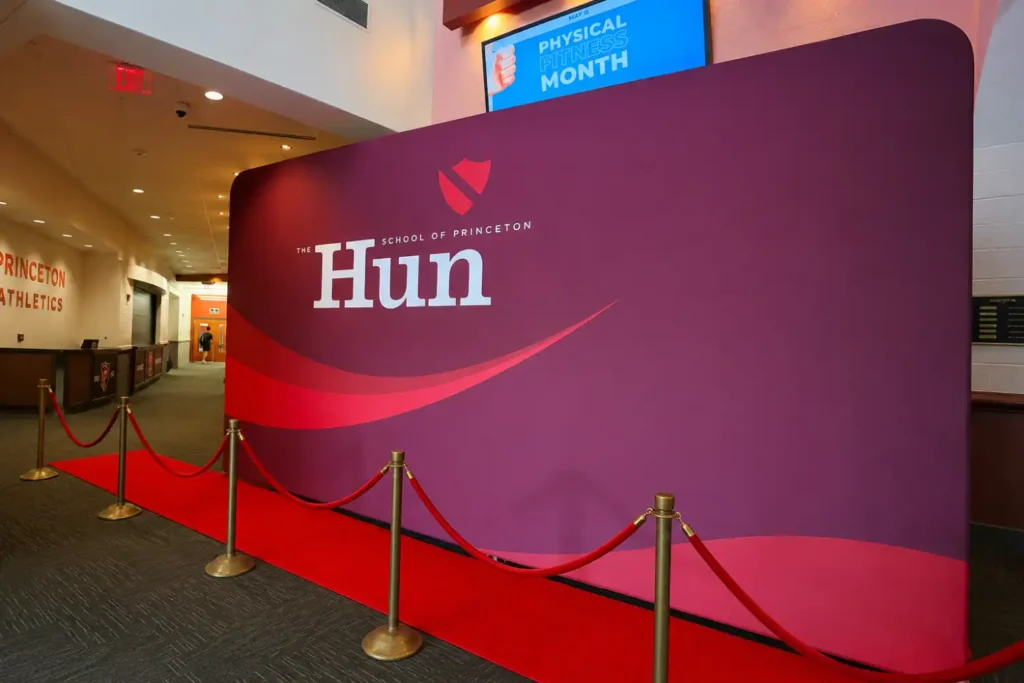 Red carpet arrival with stanchions and a custom Hun School of Princeton backdrop at the Senior Dinner, an AI sketch robot graduation event.