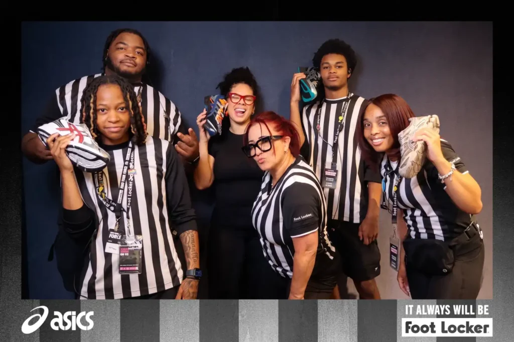 Foot Locker employees in referee shirts holding Asics sneakers at the First Day Fresh Pop-Up Photo Studio with Asics branded overlay